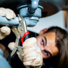 A close-up of a person using a wrench to fix a pipe under a sink. The individual, wearing gloves, is intensely focused on the task as water visibly leaks from the pipe—a scene that highlights the expertise of emergency plumbers in critical situations.